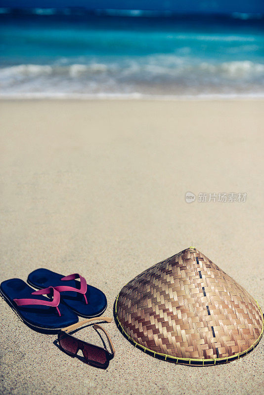 Flip Flop太阳镜和传统亚洲帽子在海滩附近的海洋